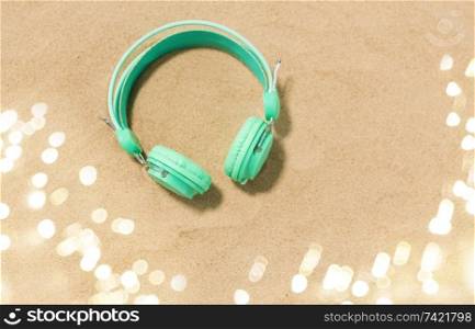music, audio equipment and vacation concept - earphones on summer beach sand. earphones on summer beach sand