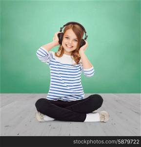 music, childhood, people and technology concept - happy girl with headphones listening to music over green chalk board background
