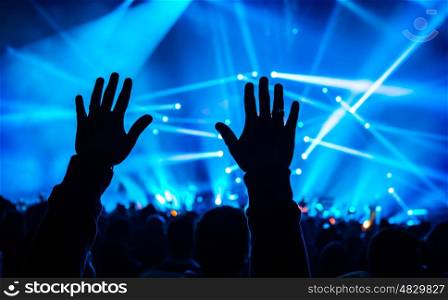 Music concert, silhouette of mans hands up, crowd of people, active night life, holiday celebration in dance club, pleasure and enjoyment concept