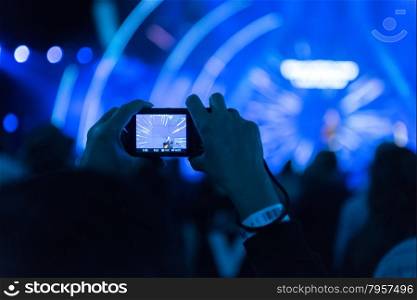 Music Concert with Hands Holding Up Single Mobile Phone Device