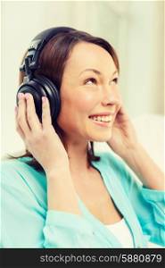 music, entertainment and happiness concept - happy and smiling woman with headphones at home
