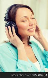 music, entertainment and happiness concept - happy and smiling woman with headphones at home