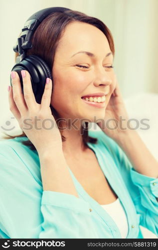 music, entertainment and happiness concept - happy and smiling woman with headphones at home