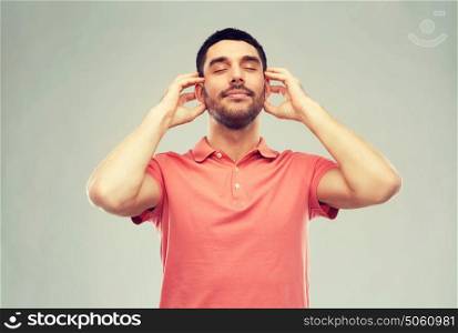 music, gesture and people concept - happy smiling man listening to music with imaginary headphones over gray background. happy man listening to music over gray background
