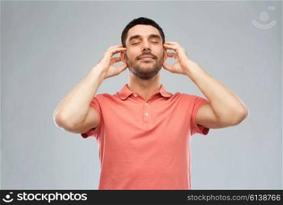music, gesture and people concept - happy smiling man listening to music with imaginary headphones over gray background