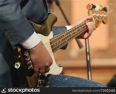 music, hand musician playing bass guitar close-up