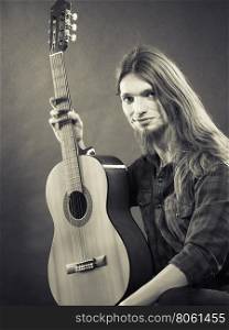 Music, hobby concept. Black and white picture with artist. Young man is holding his beloved guitar.