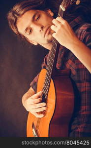 Music, hobby concept. Focused hippie with his guitar. Holding the instrument and playing the song.