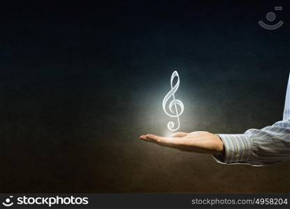 Music icon in hand. Hand of man hold music note icon in palm