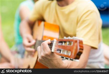 music, leisure and people concept - close up of man playing guitar at camping