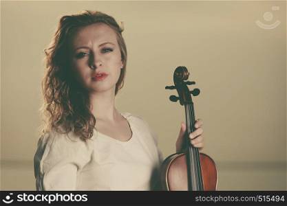 Music love, hobby and everyday passion concept. Woman on beach near sea holding violin during sunset. Woman on beach near sea holding violin