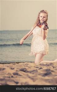 Music love, hobby and everyday passion concept. Woman on beach near sea playing on violin. Woman on beach near sea holding violin