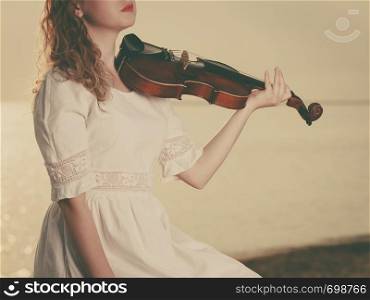 Music love, hobby and everyday passion concept. Woman on pier outside holding violin during sunset. Woman on pier outside holding violin