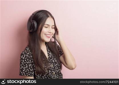 Music lover woman is enjoying with headset on pink background