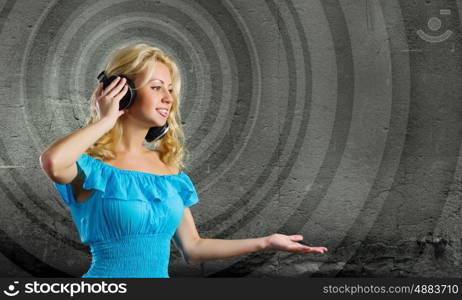 Music lover. Young blond girl in blue dress listening music