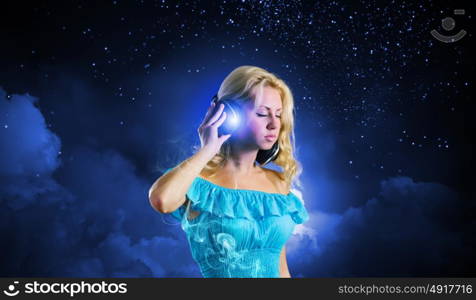 Music lover. Young blond girl in blue dress listening music