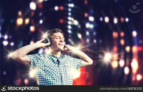 Music lover. Young handsome man in earphones enjoying the music