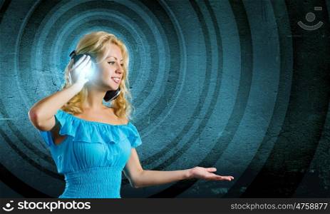 Music lover. Young lady in blue dress with headphones enjoying the music
