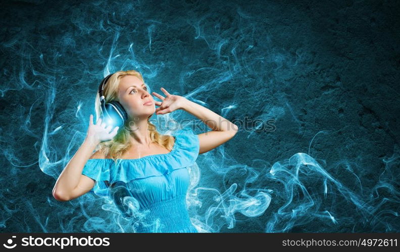 Music lover. Young lady in blue dress with headphones enjoying the music