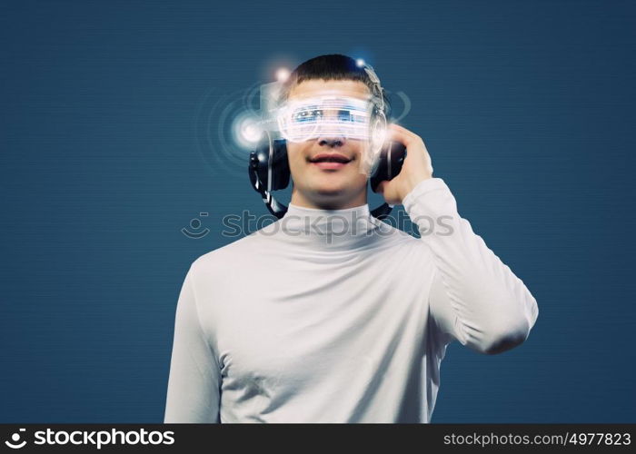 Music lover. Young man wearing headphones against media background. New technologies