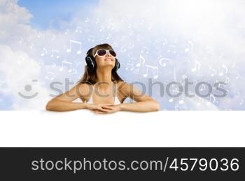 Music lover. Young pretty girl in bikini with blank banner