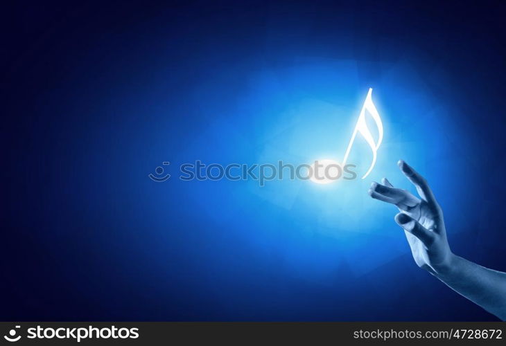 Music note. Close up of person hand touching music symbol on blue background