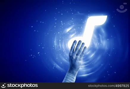 Music note. Close up of person hand touching music symbol on blue background