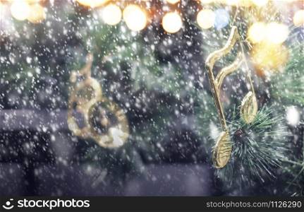 Music note decoration on christmas tree with snow falling in the winter