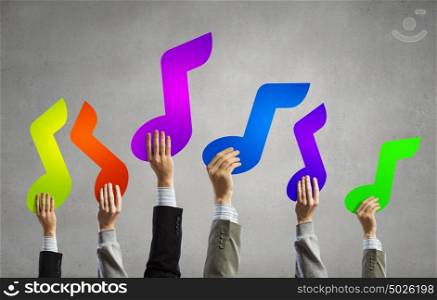 Music notes in hands. Group of people hands holding colorful music symbols