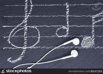 Music notes with treble clef and headphones on black stone ackground. Music notes with  headphones 