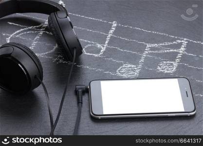 Music notes with treble clef, smartphone  and headphones, copy space on screen. Music notes with  headphones 