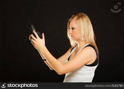 Music, passion concept. Studio shot of blonde young woman holding big headphones.. Blonde woman holding big headphones in studio