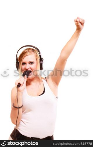 Music, passion concept. Studio shot of blonde young woman singing to microphone and wearing big headphones on her head performing songs and having fun, isolated. Woman singing to microphone wearing headphones