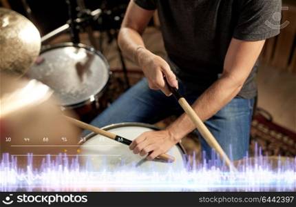music, people and entertainment concept - close up of male musician with drumsticks playing drum kit at concert at sound recording studio. musician playing drums at sound recording studio