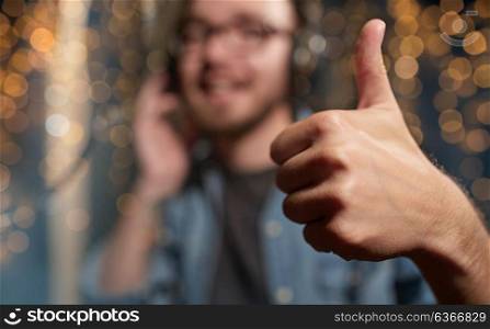 music, people and gesture concept - hand of singer showing thumbs up at sound recording studio over holidays lights background. singer showing thumbs up at sound recording studio