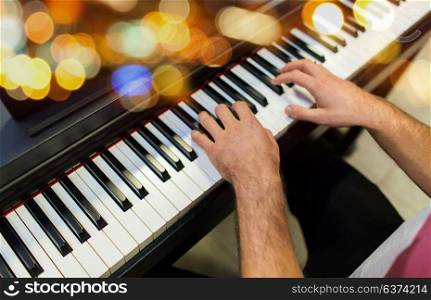 music, people and instruments concept - close up of male hands playing piano over lights. close up of male hands playing piano