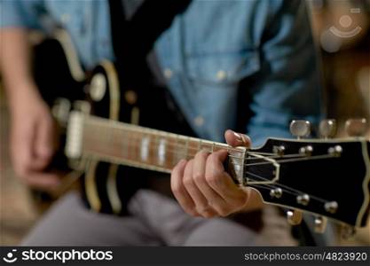 music, people, musical instruments and entertainment concept - close up of male guitarist playing electric guitar at studio rehearsal
