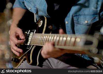 music, people, musical instruments and entertainment concept - close up of male guitarist playing electric guitar at studio rehearsal