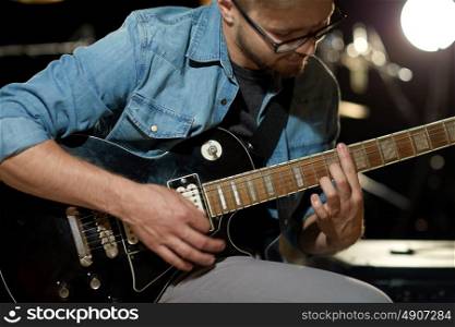 music, people, musical instruments and entertainment concept - close up of male guitarist playing electric guitar at studio rehearsal. close up of man playing guitar at studio rehearsal