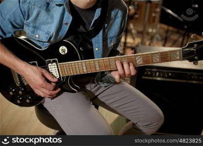 music, people, musical instruments and entertainment concept - male guitarist playing electric guitar at studio rehearsal
