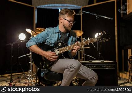 music, people, musical instruments and entertainment concept - male guitarist playing electric guitar at studio rehearsal