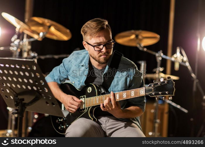 music, people, musical instruments and entertainment concept - male guitarist playing electric guitar at studio rehearsal