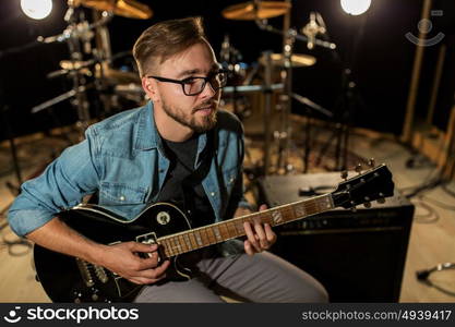 music, people, musical instruments and entertainment concept - male guitarist playing electric guitar at studio rehearsal. man playing guitar at studio rehearsal