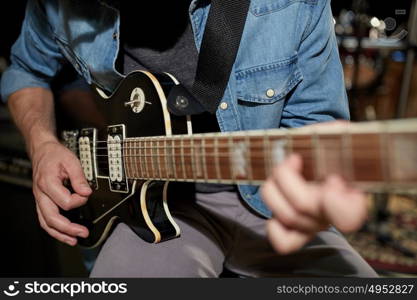 music, people, musical instruments and entertainment concept - male guitarist playing electric guitar at studio rehearsal. man playing guitar at studio rehearsal