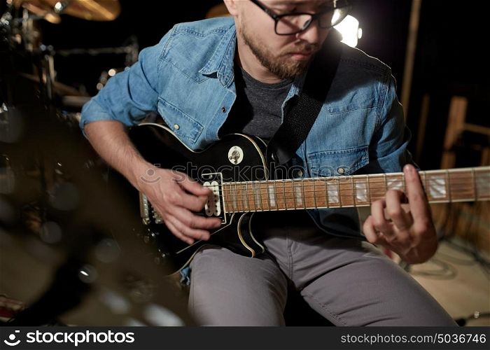 music, people, musical instruments and entertainment concept - male guitarist playing electric guitar at studio rehearsal. man playing guitar at studio rehearsal