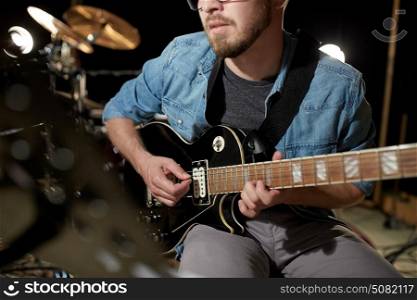 music, people, musical instruments and entertainment concept - male guitarist playing electric guitar at studio rehearsal. man playing guitar at studio rehearsal