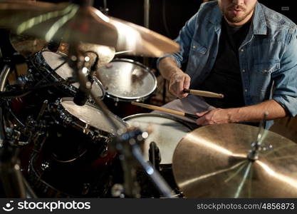 music, people, musical instruments and entertainment concept - male musician playing drums and cymbals at concert or studio