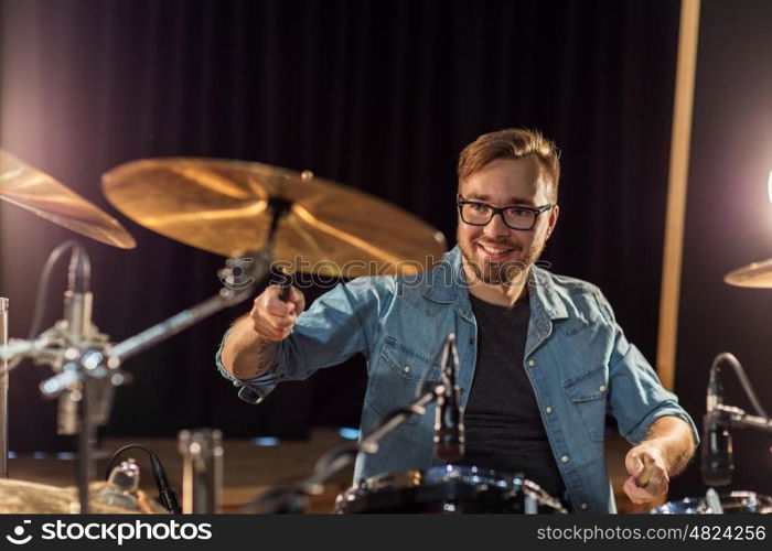 music, people, musical instruments and entertainment concept - male musician with drumsticks playing drums and cymbals at concert or studio