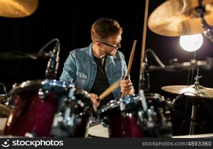 music, people, musical instruments and entertainment concept - male musician with drumsticks playing drums and cymbals at concert or studio