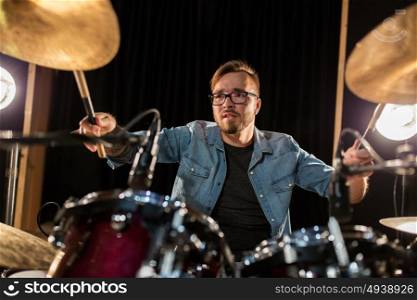 music, people, musical instruments and entertainment concept - male musician with drumsticks playing drums and cymbals at concert or studio. male musician playing drums and cymbals at concert